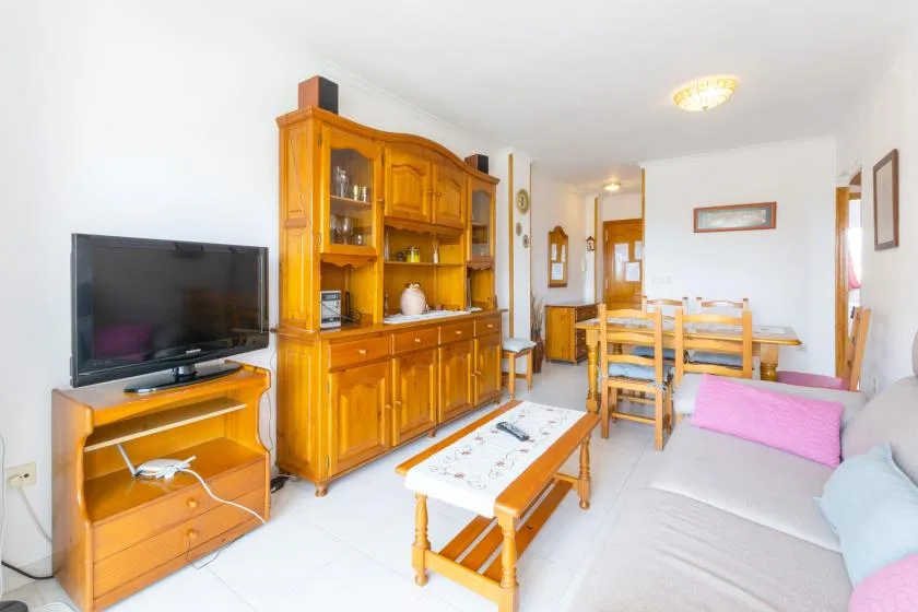 A living and dining room with wooden furniture, a television, and a dining table.