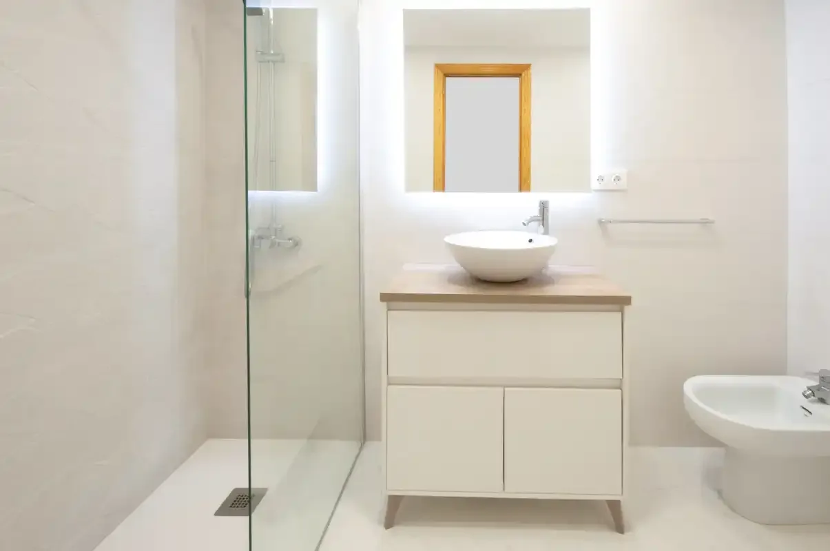 A bright bathroom with a vanity, mirror, and glass shower.