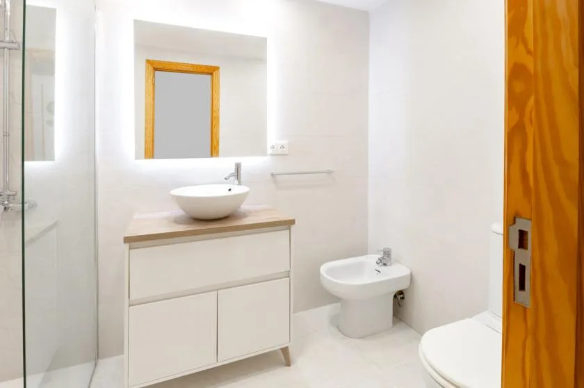 A bright bathroom with a sink vanity, bidet, and shower.
