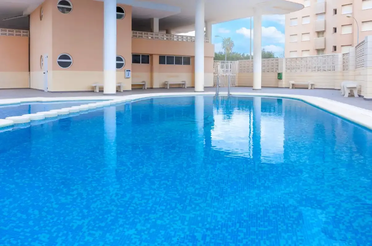 A swimming pool fills an outdoor courtyard beside surrounding buildings.