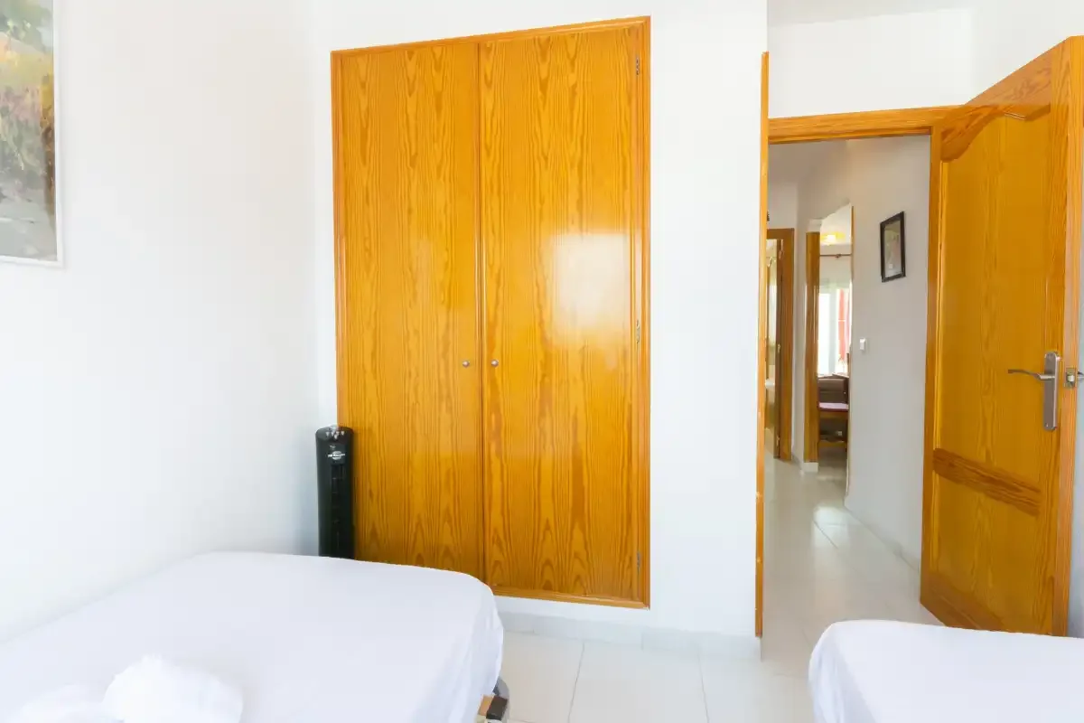 A bedroom with wooden wardrobes and an open doorway to a hallway.