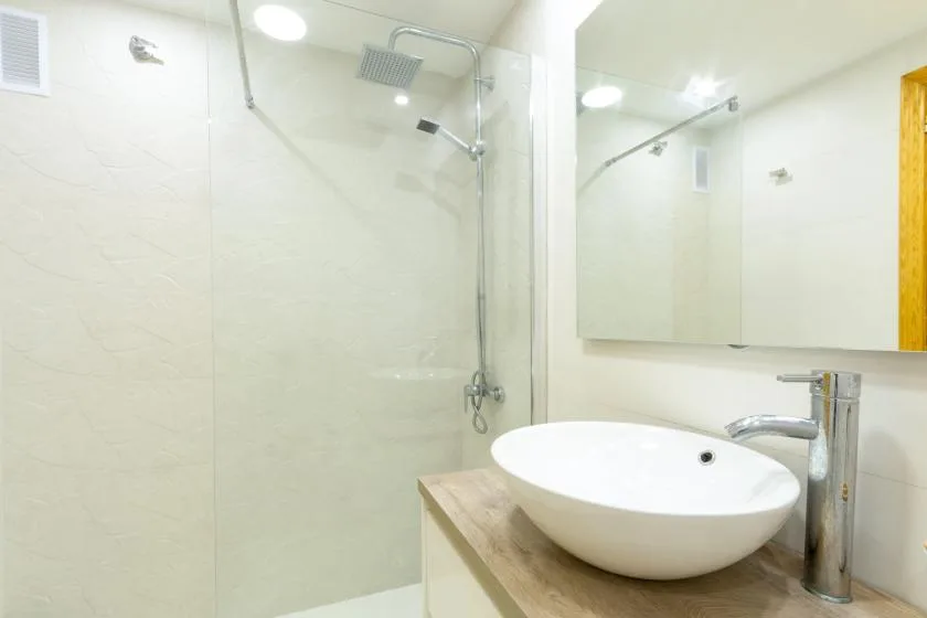 A bright bathroom with a vessel sink and wall-mounted shower.