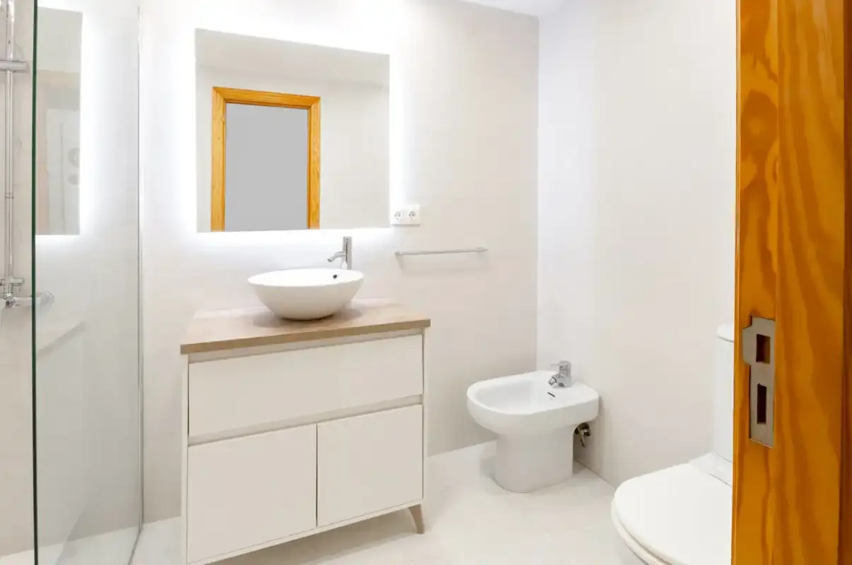 A bright bathroom with a sink vanity, bidet, and toilet.