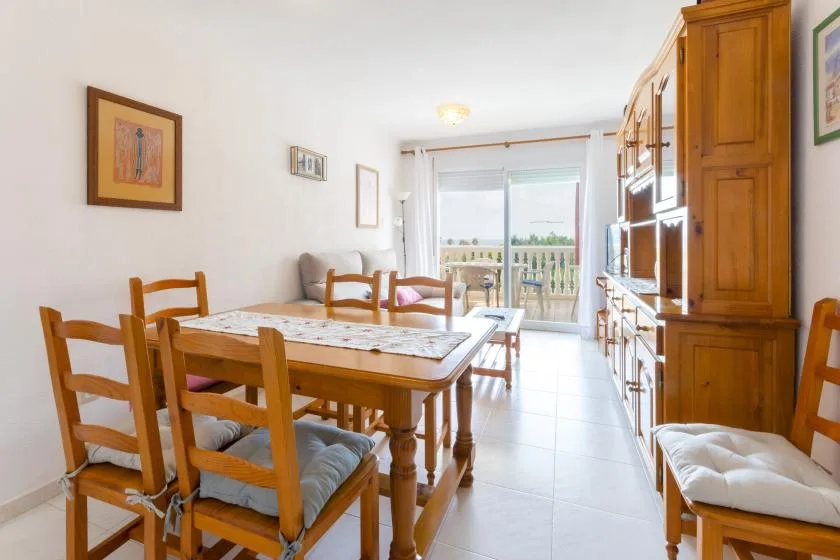A dining room with a wooden table and seating beside large windows.
