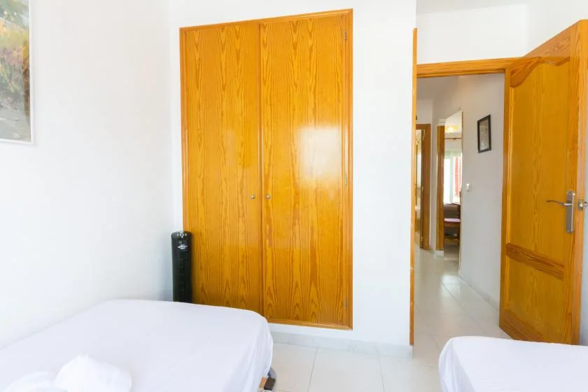 A bedroom with a bed beside wooden wardrobes and an open doorway.