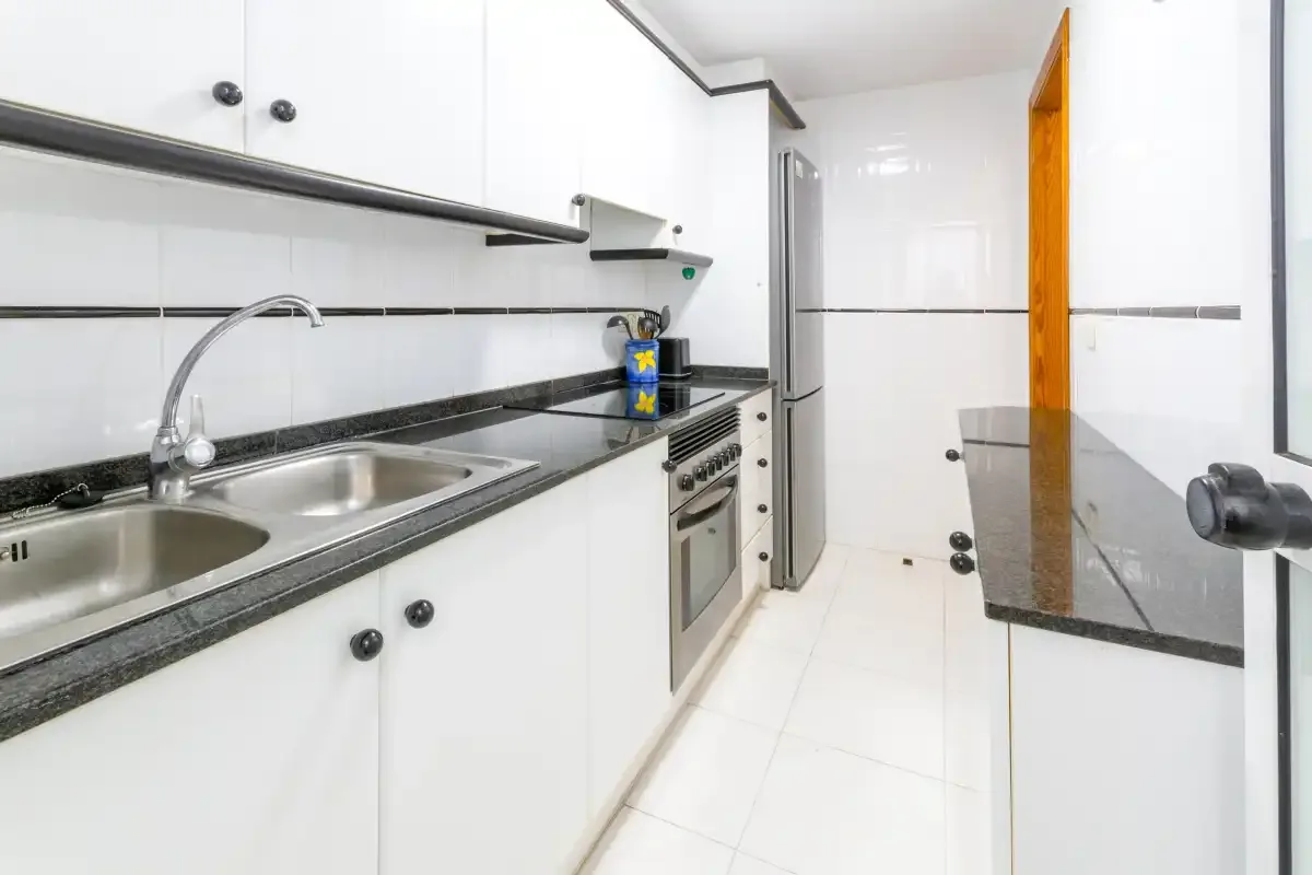 A bright kitchen with white cabinets, a countertop, and a built-in oven.