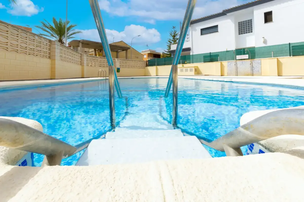 An outdoor swimming pool with steps leading into the water.