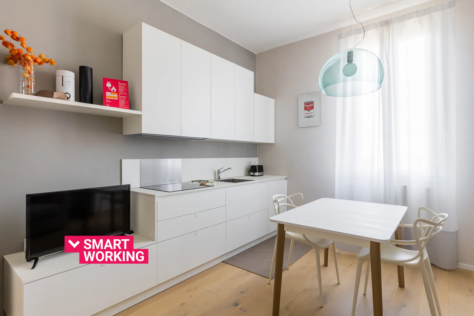 Una cocina y comedor luminosos con armarios blancos, una mesa y sillas.