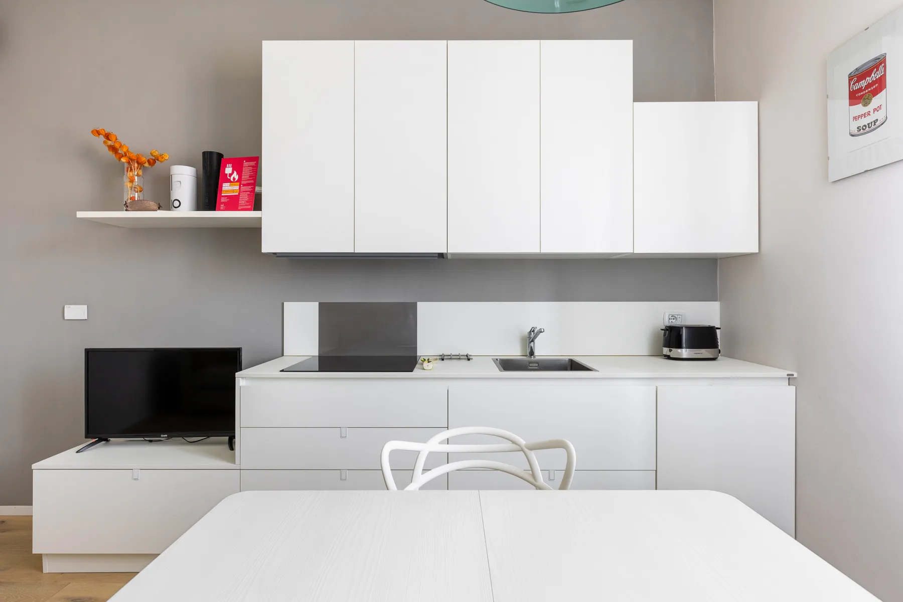 Una cocina moderna con armarios blancos, una encimera y una mesa de comedor.