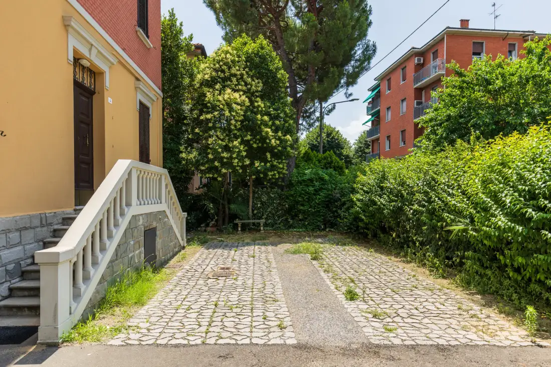 Un patio exterior pavimentado está rodeado de edificios y vegetación frondosa.