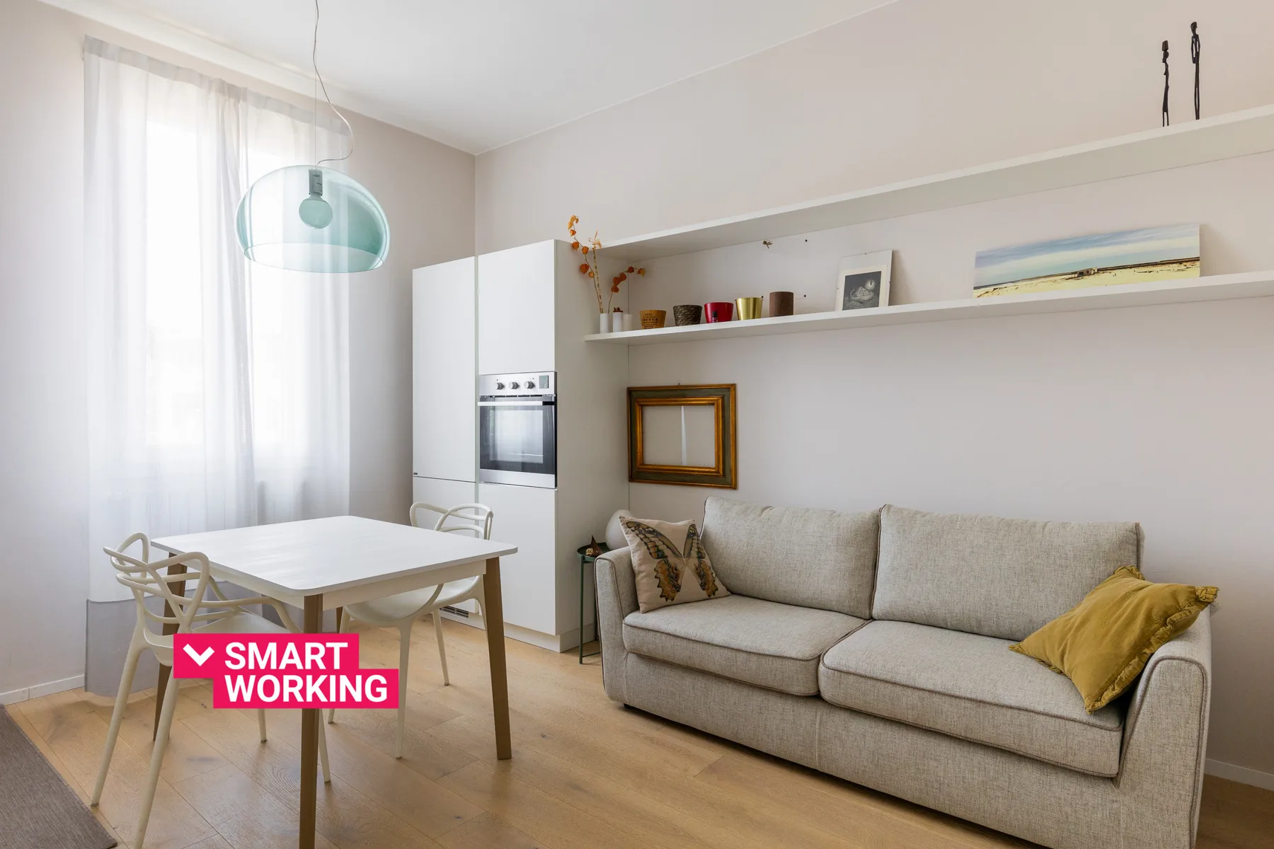 Una luminosa sala de estar y comedor con sofá, mesa y grandes ventanas.