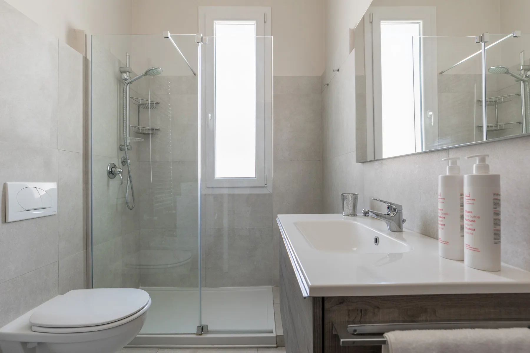 Un baño luminoso con ducha de vidrio, inodoro y tocador.