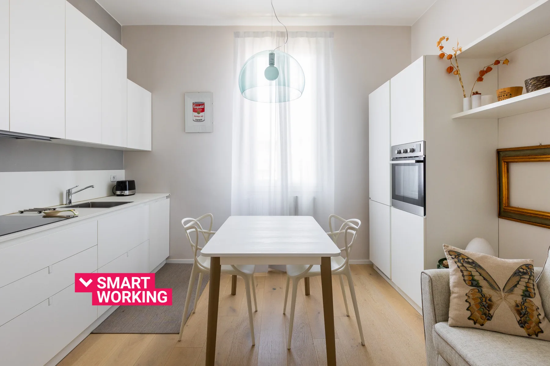 Una cocina-comedor luminosa con gabinetes blancos y una mesa junto a la ventana.