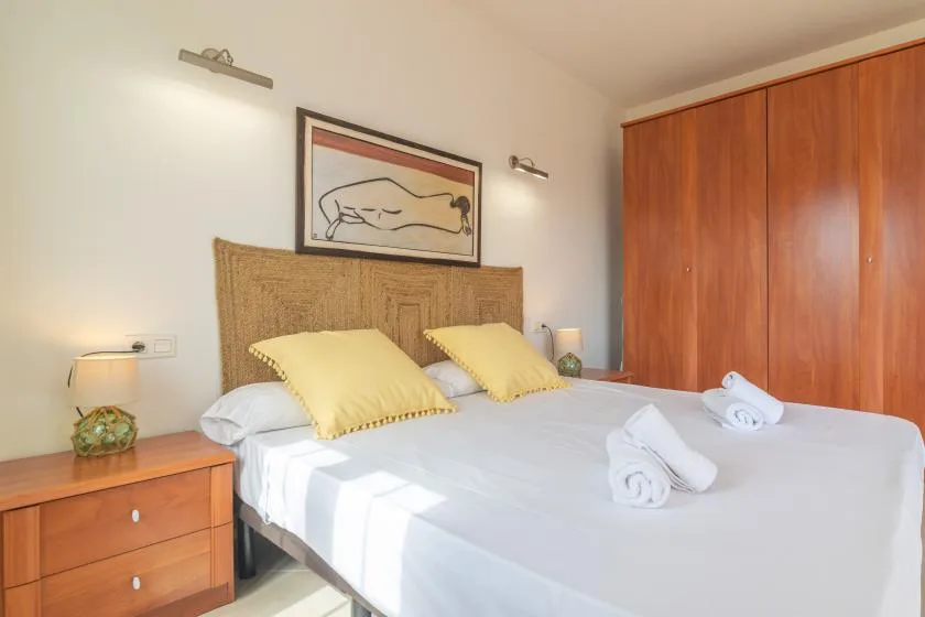 Un dormitorio con una cama tendida y un armario de madera.