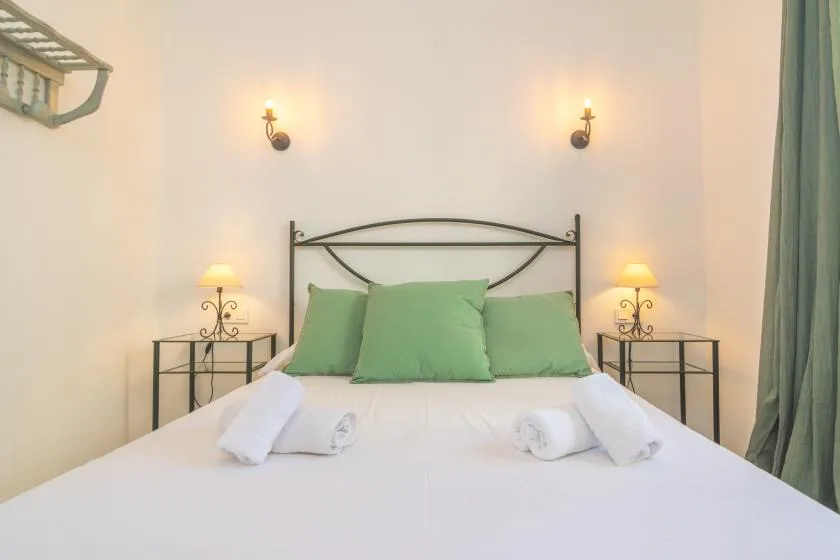 Un dormitorio con una cama bien tendida y almohadas verdes.
