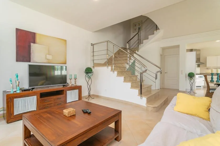 Una sala de estar luminosa con una mesa de centro de madera y una escalera.