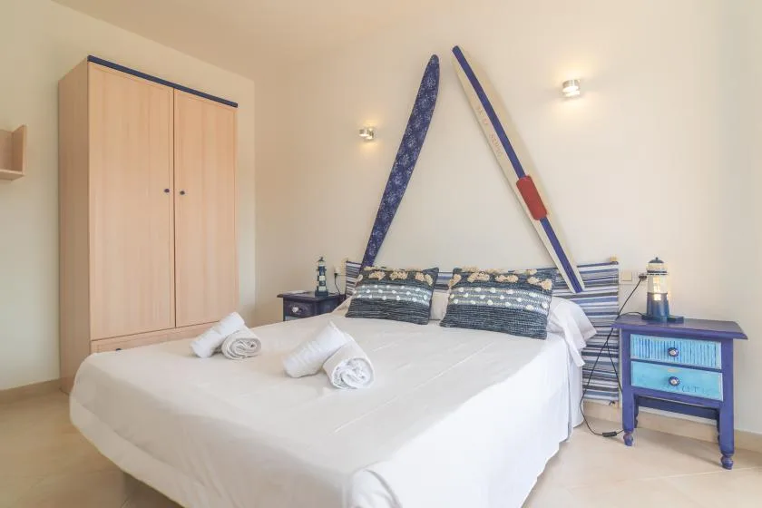 Un dormitorio con una cama bien hecha, almohadas estampadas y un armario de madera.