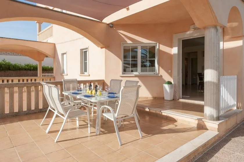 A tiled outdoor patio with a dining table and seating beneath a canopy.