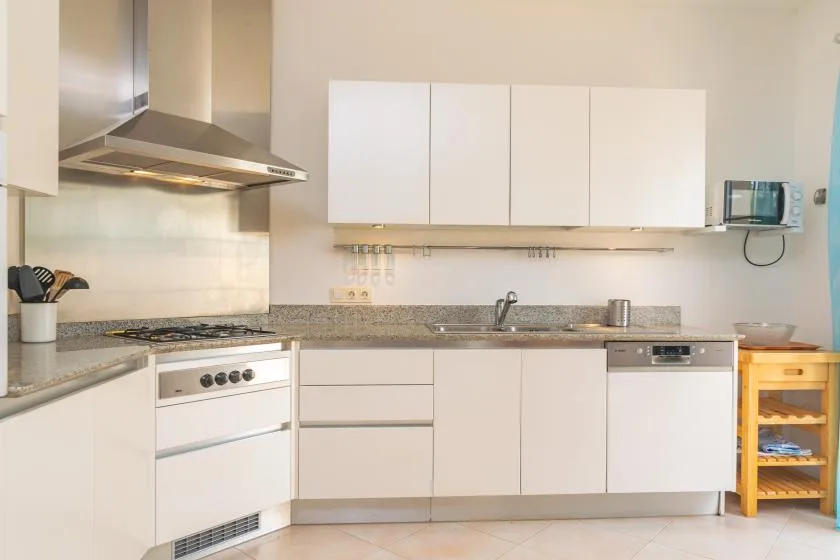 Una cocina luminosa con armarios blancos, encimera y electrodomésticos de cocina.