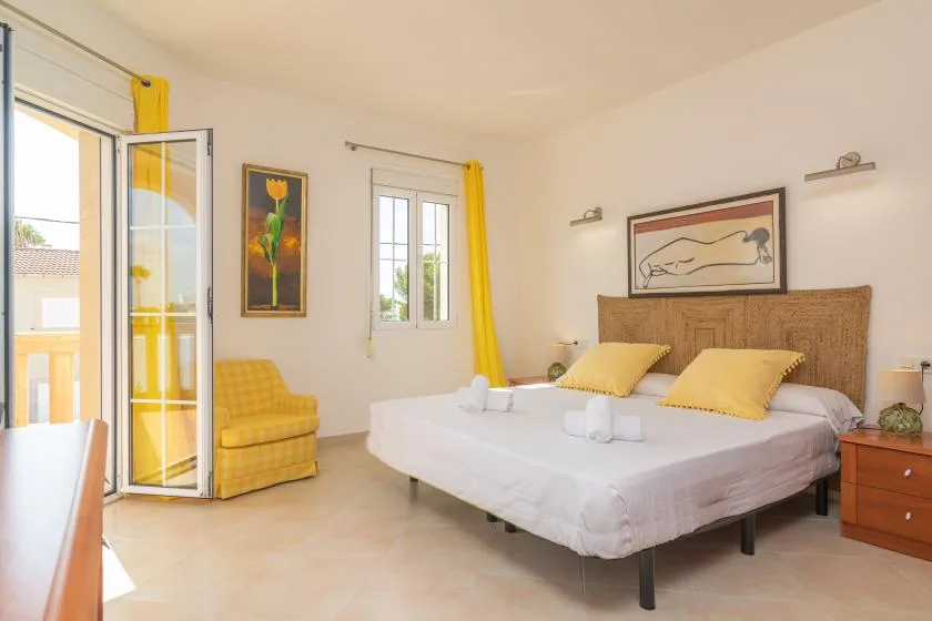 Un dormitorio luminoso con una cama bien hecha y detalles amarillos.