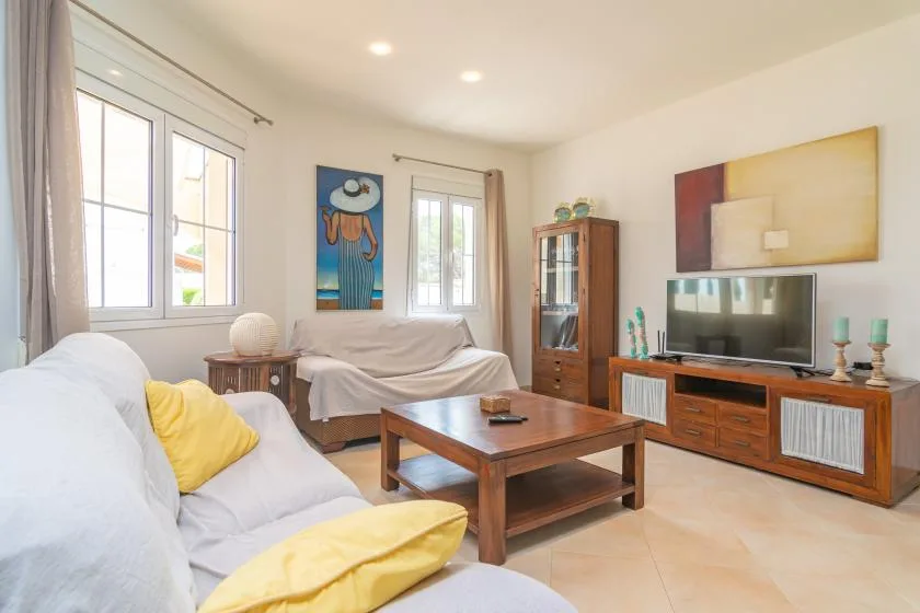 Una sala luminosa con asientos, una mesa de centro y un televisor.