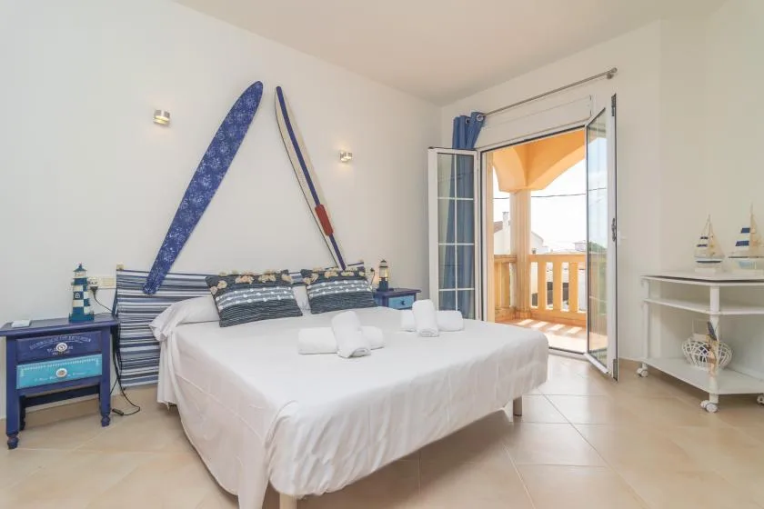 Un dormitorio con una cama grande y una puerta abierta a un balcón.