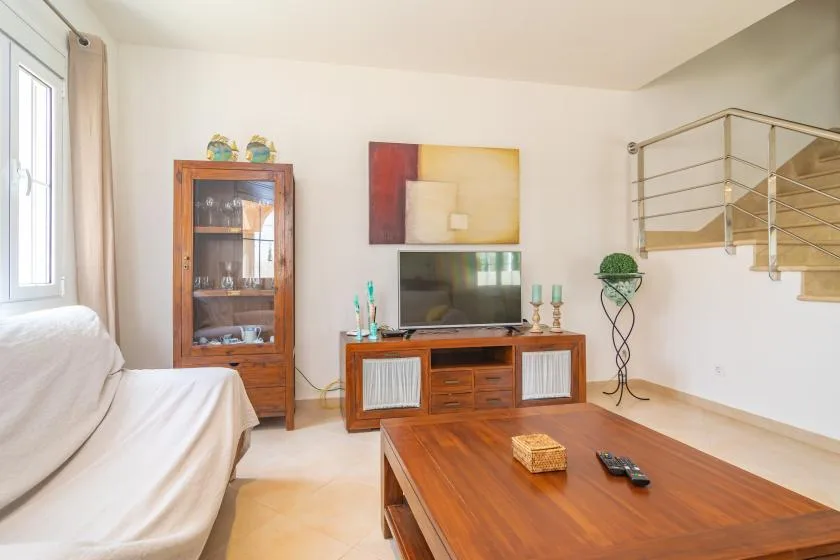 Una sala luminosa con asientos, un televisor y una mesa de centro de madera.
