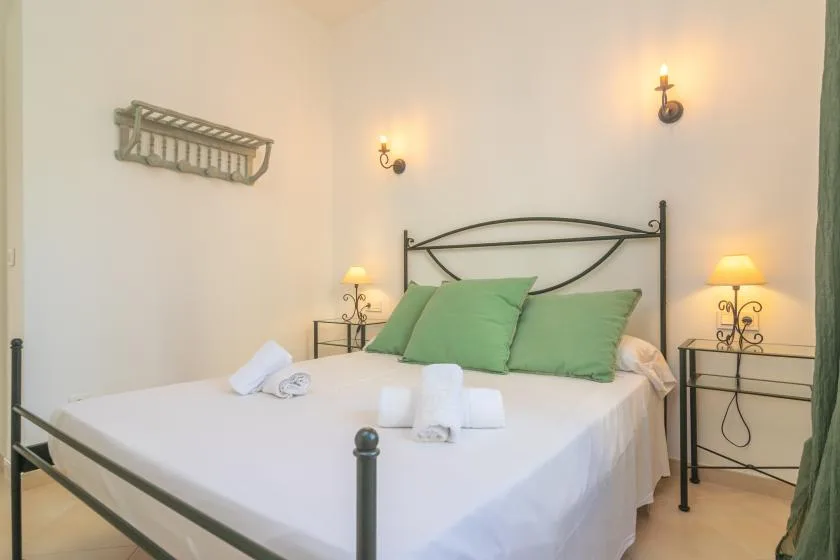 Un dormitorio con una cama bien tendida y almohadas verdes.