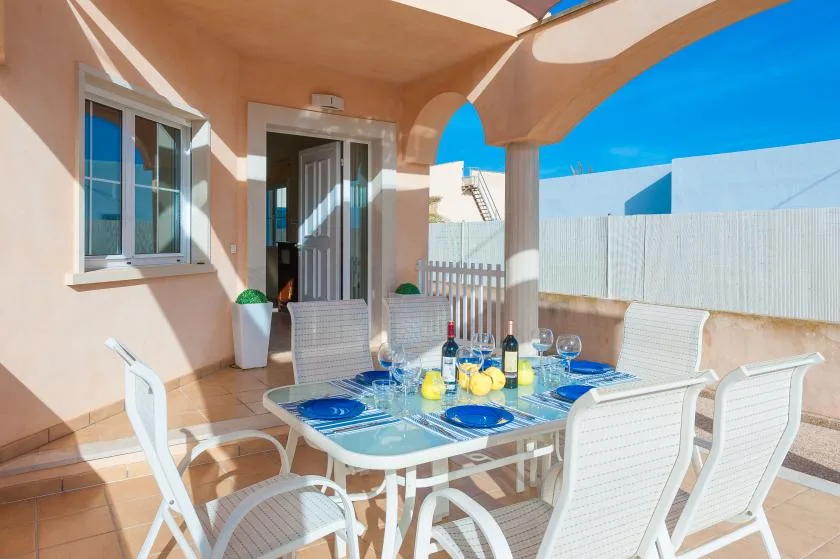 A covered outdoor dining area with a table set beside the house.