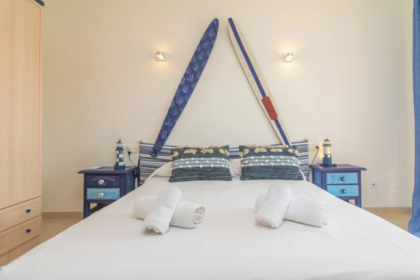 Un dormitorio con una cama, almohadas estampadas y correas decorativas azules en la pared.