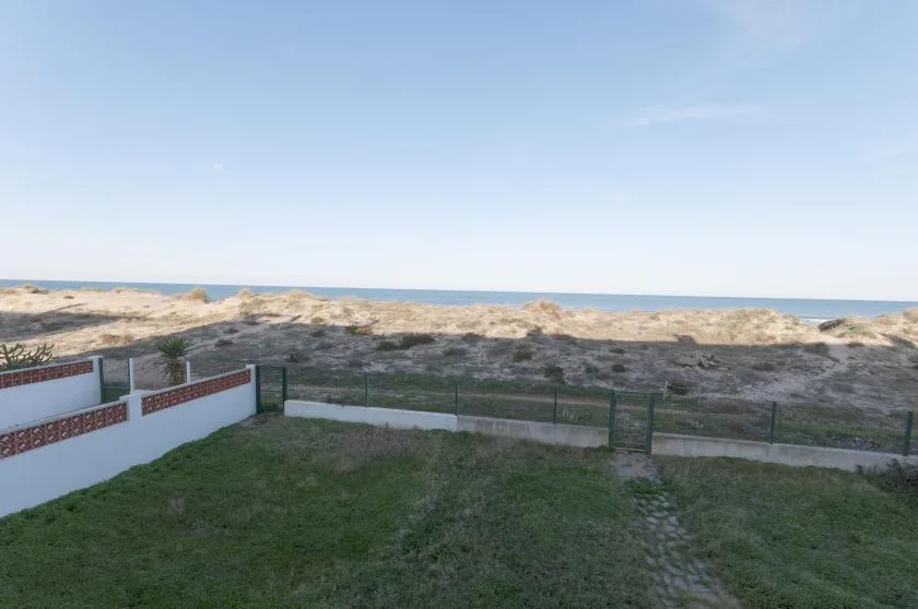 Un patio con césped da a dunas bajas y al océano.
