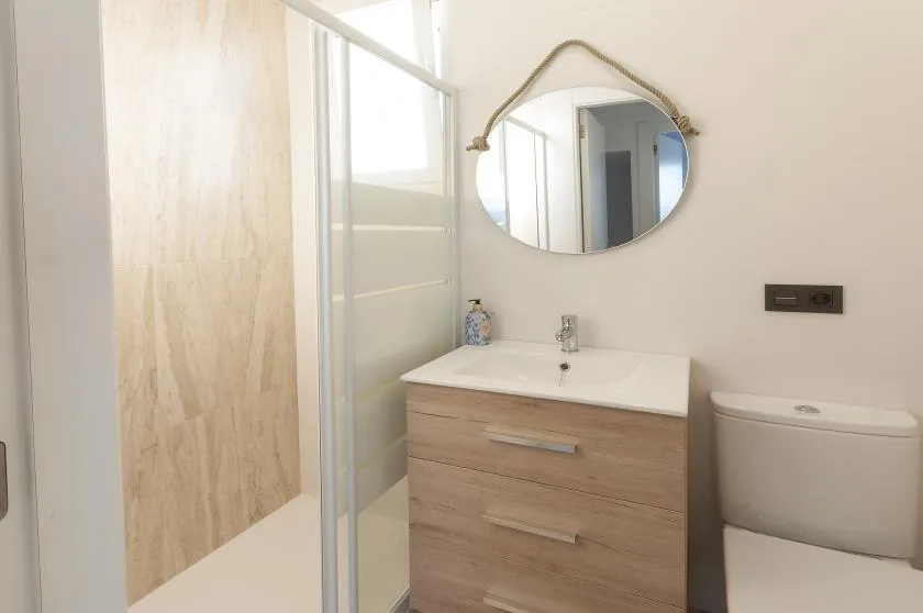Un lavabo con espejo está junto a una ducha de vidrio.