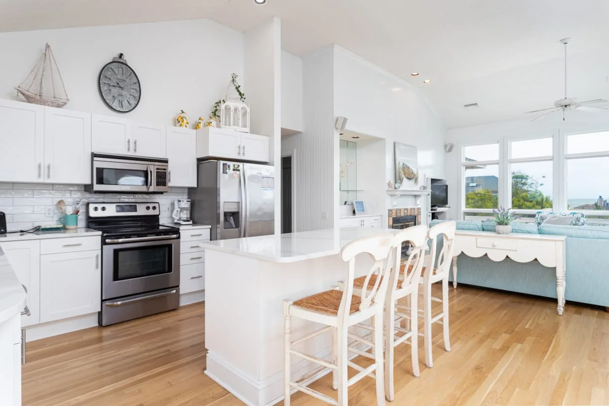 A bright open kitchen and dining area with a white island and window-side table.