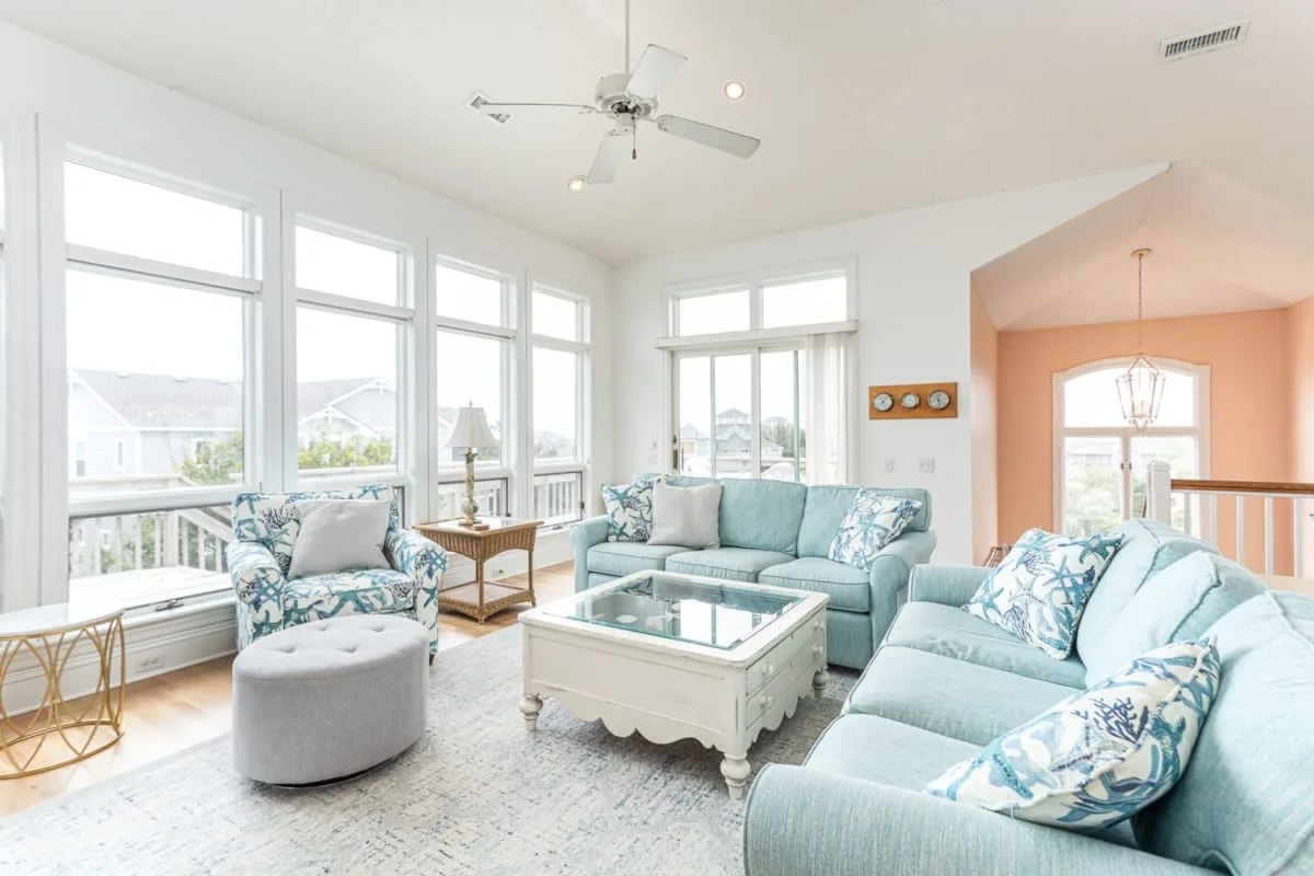 A bright living room with seating arranged around a glass-topped coffee table.