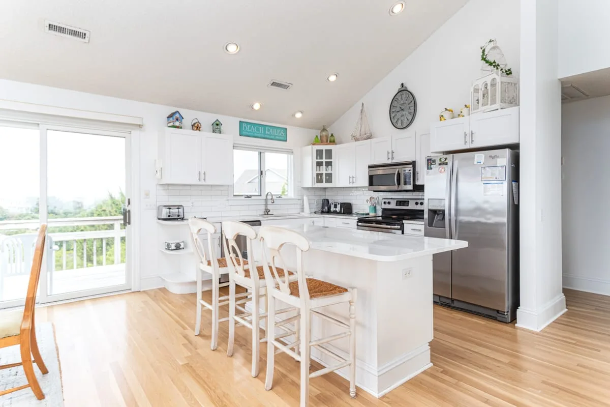 A bright kitchen with a white island and bar seating.