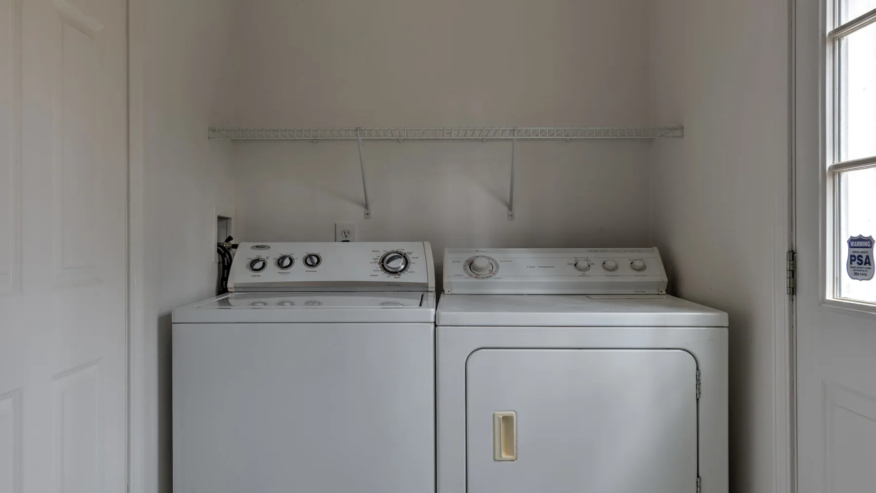 Una zona de lavandería con lavadora y secadora bajo un tendedero de pared.