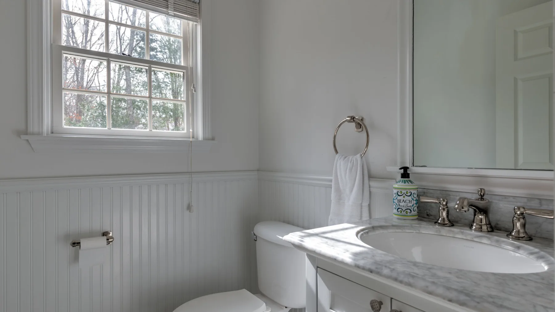 Un baño luminoso con ventana, bañera y lavabo con mueble.