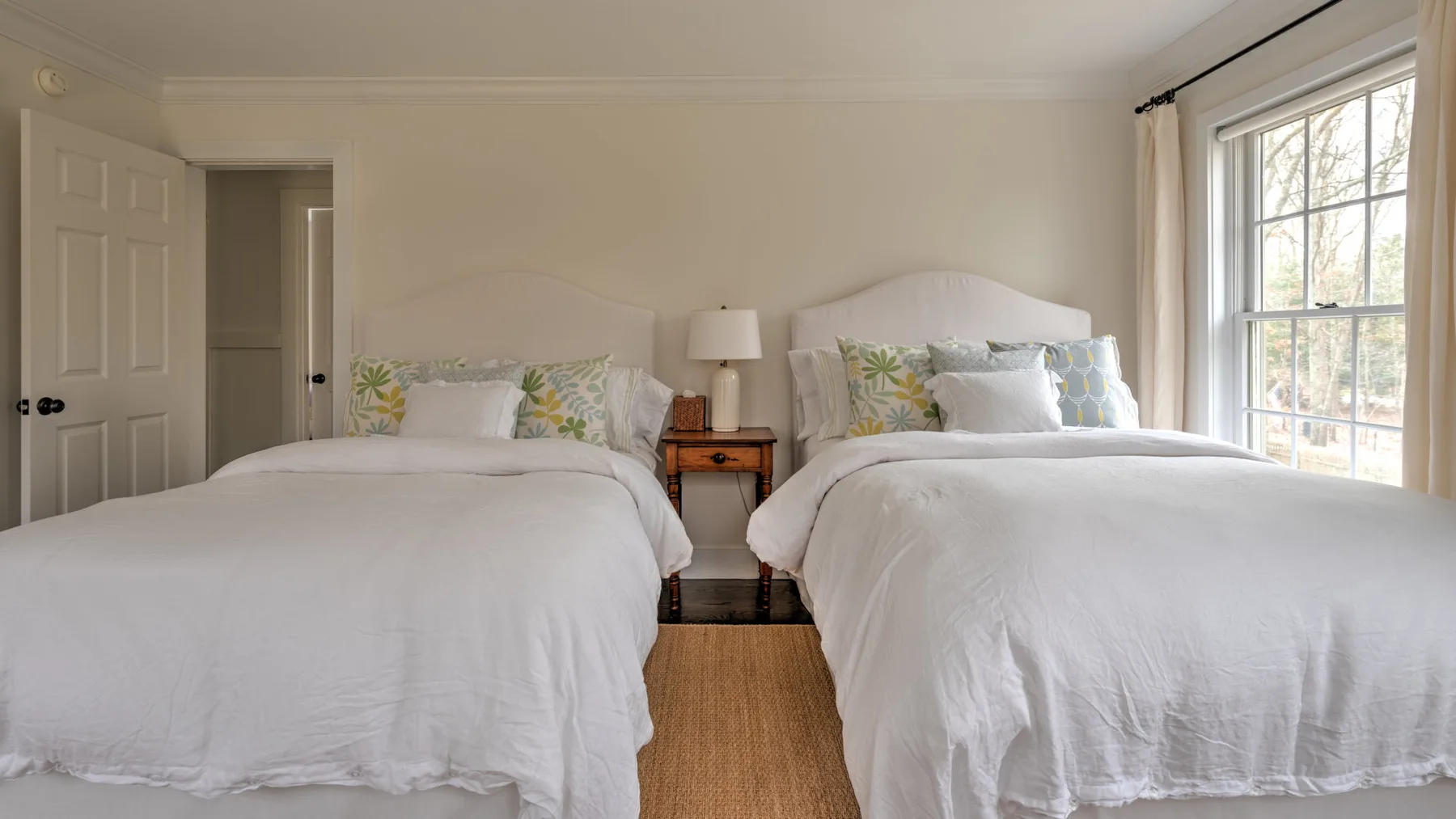 Un dormitorio luminoso con dos camas vestidas con ropa de cama blanca.