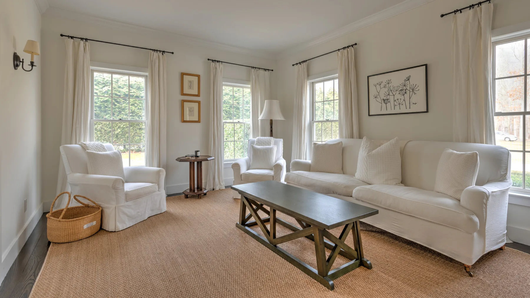 Una sala luminosa con asientos claros, ventanas altas y una mesa de centro baja.
