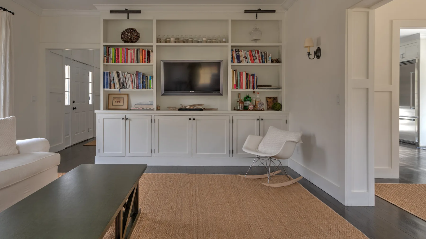 Una sala luminosa con estanterías empotradas, un televisor y asientos.
