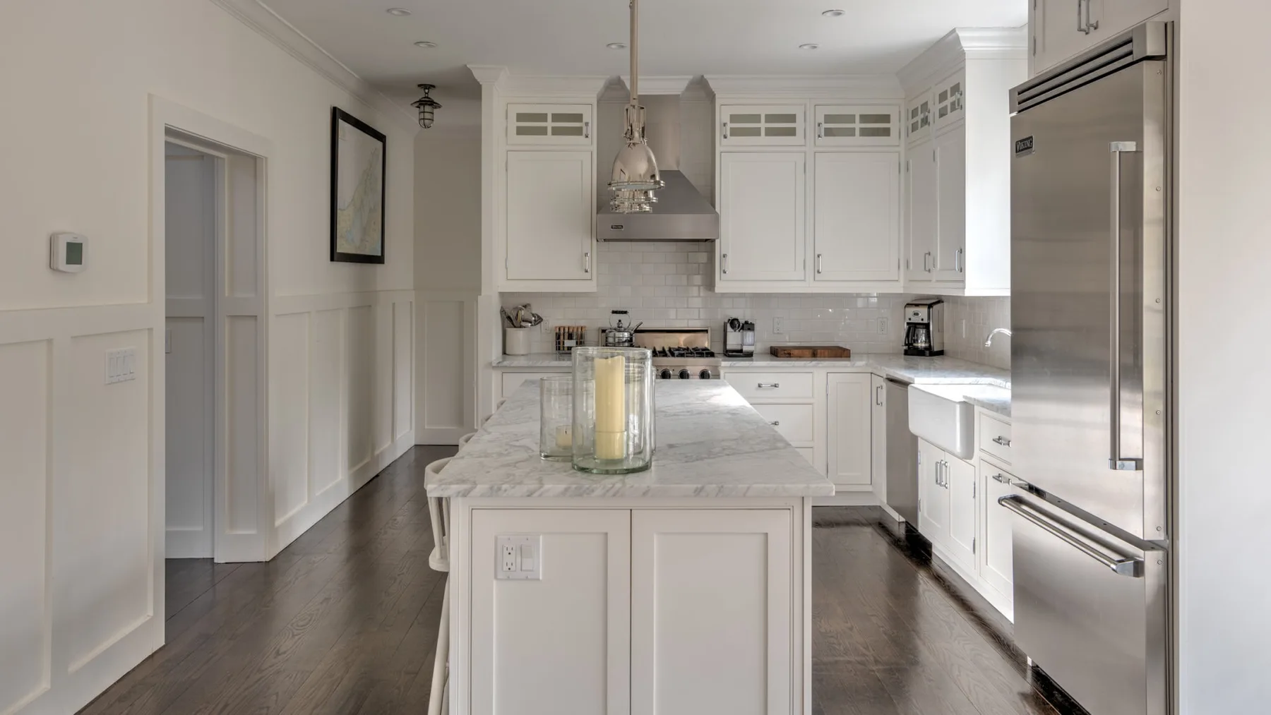 Una cocina luminosa con gabinetes blancos, una isla central y electrodomésticos de acero inoxidable.