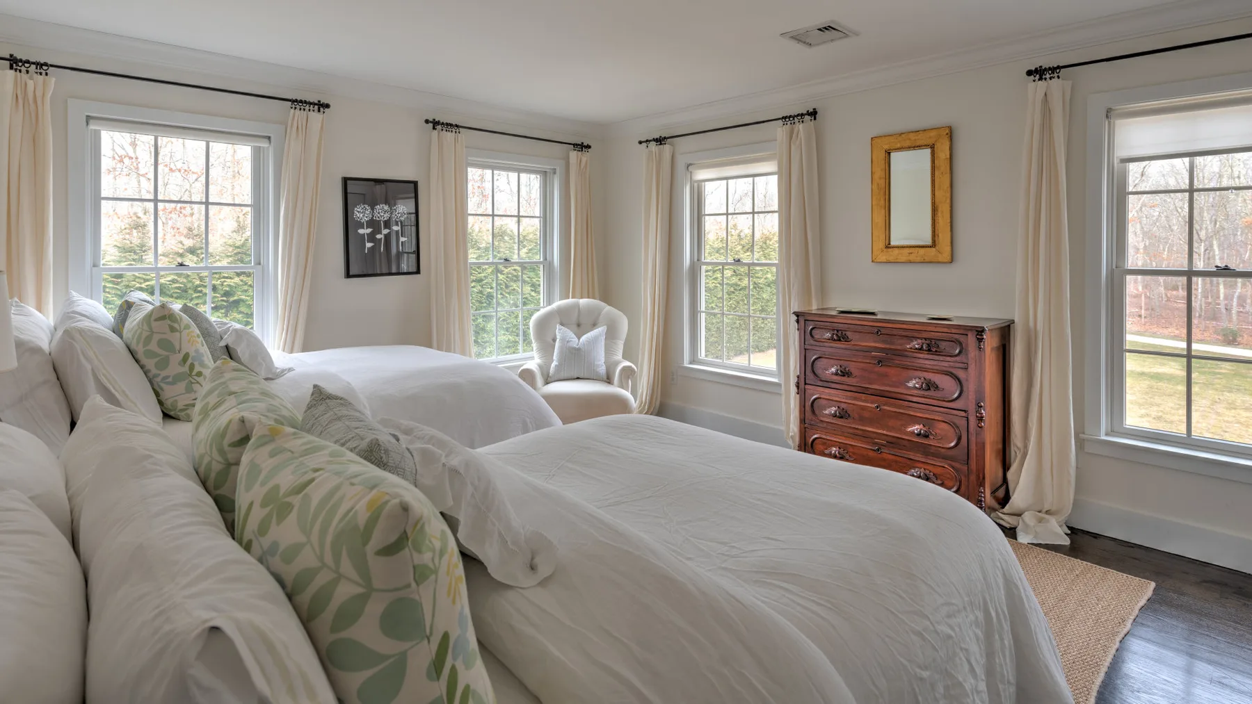 Un dormitorio luminoso con ropa de cama blanca y varias ventanas grandes.