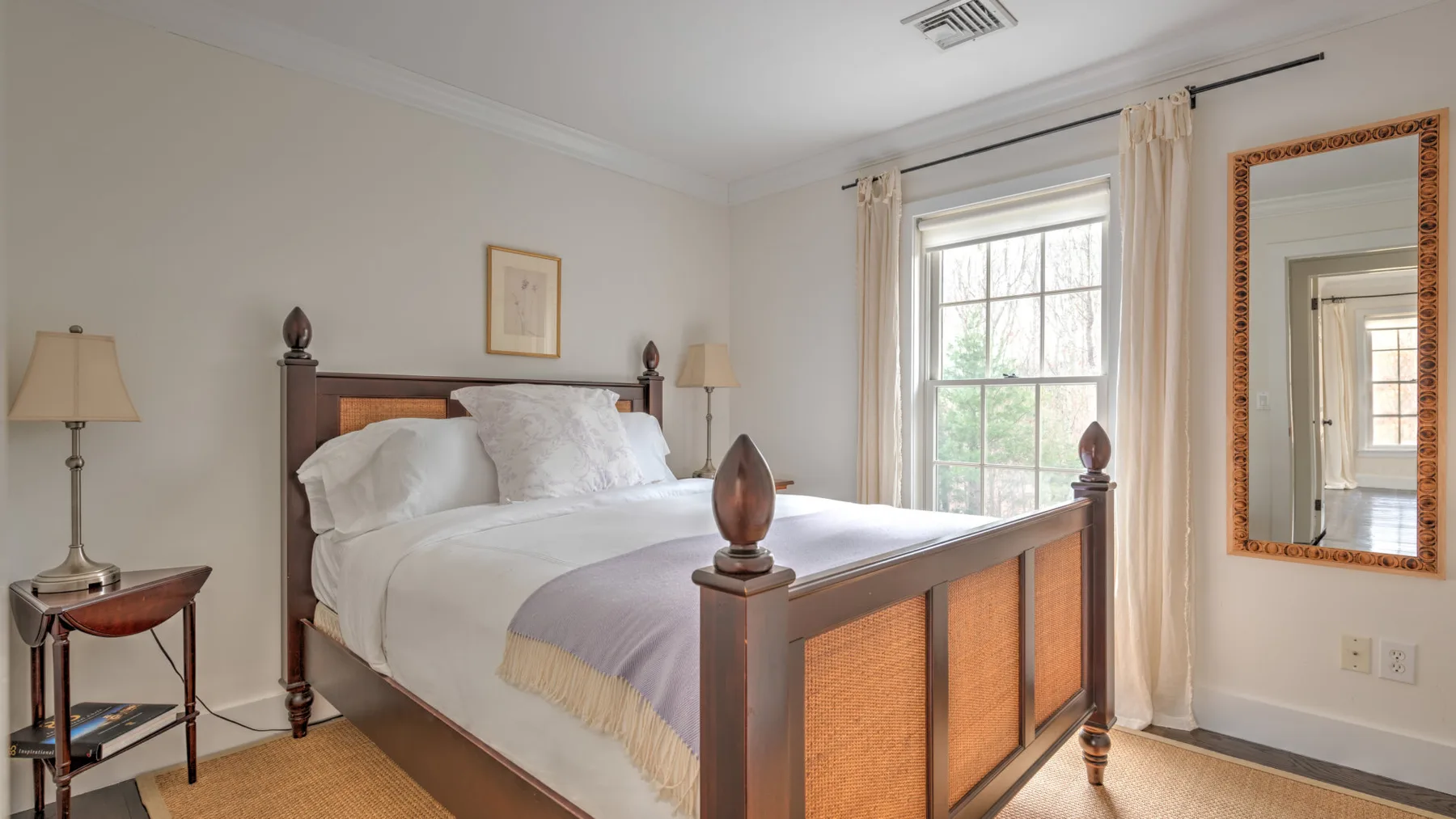 Un dormitorio con una cama de madera, ropa de cama blanca y una ventana.