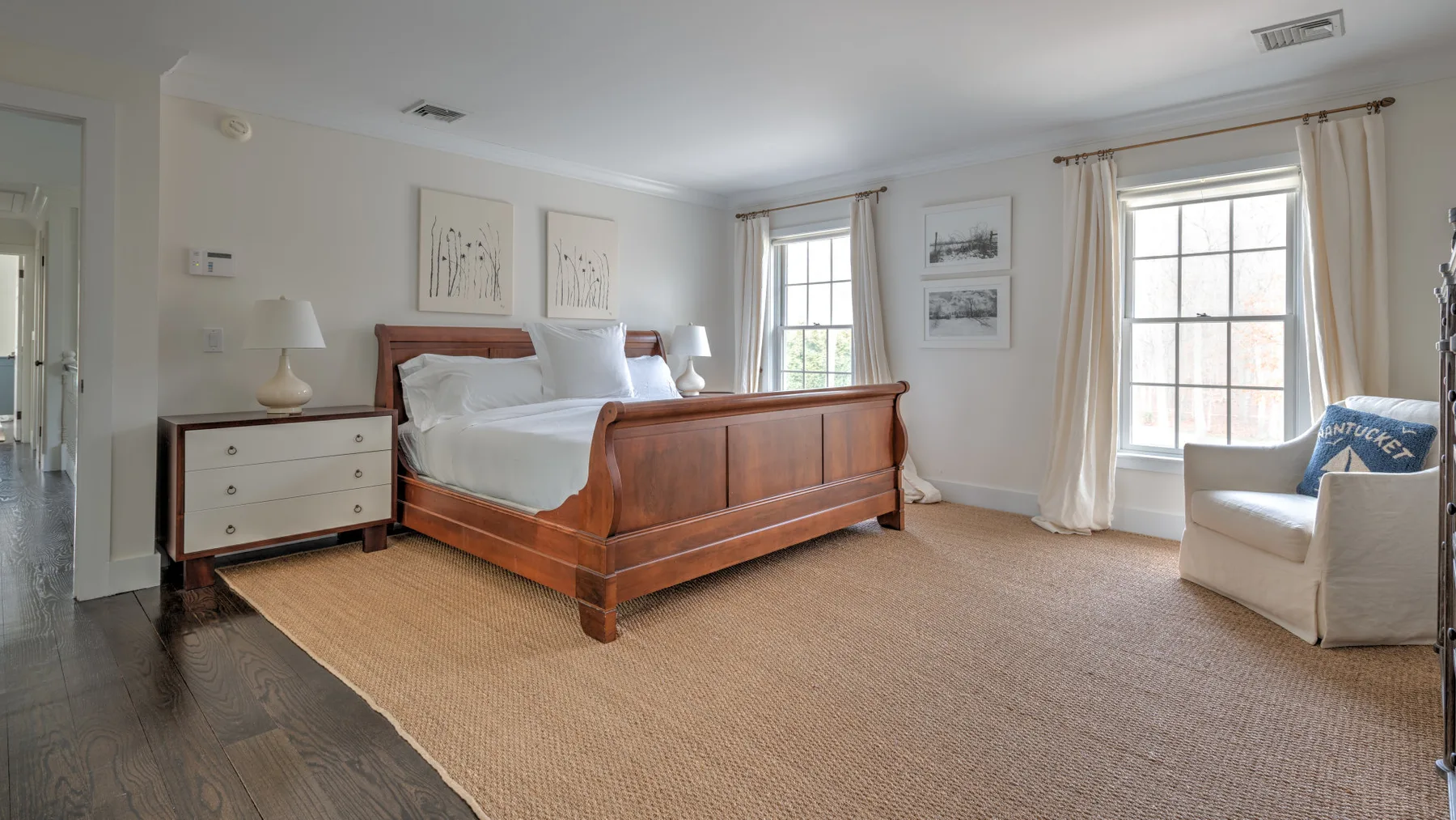 Un dormitorio con una cama de madera, una mesita de noche y dos ventanas luminosas.