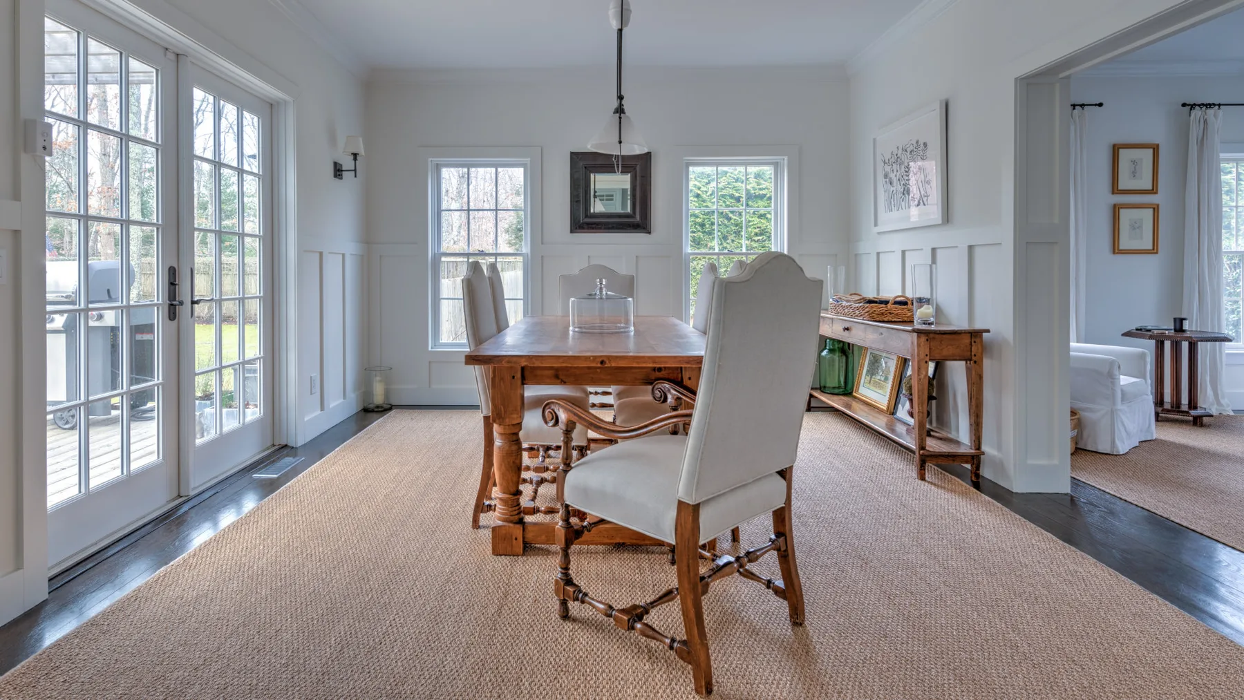 Un comedor luminoso con una mesa de madera y ventanas grandes.