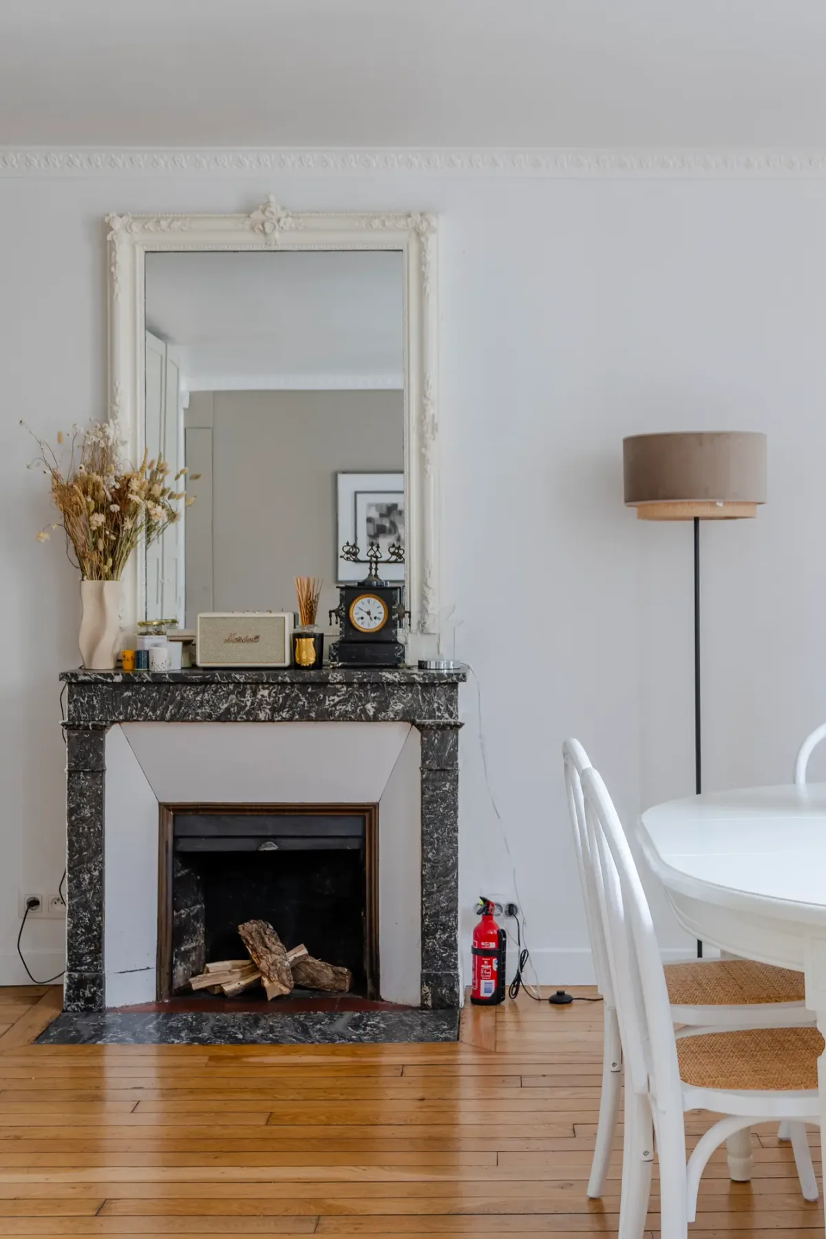 A dining area with a fireplace, mirror, and round white table.