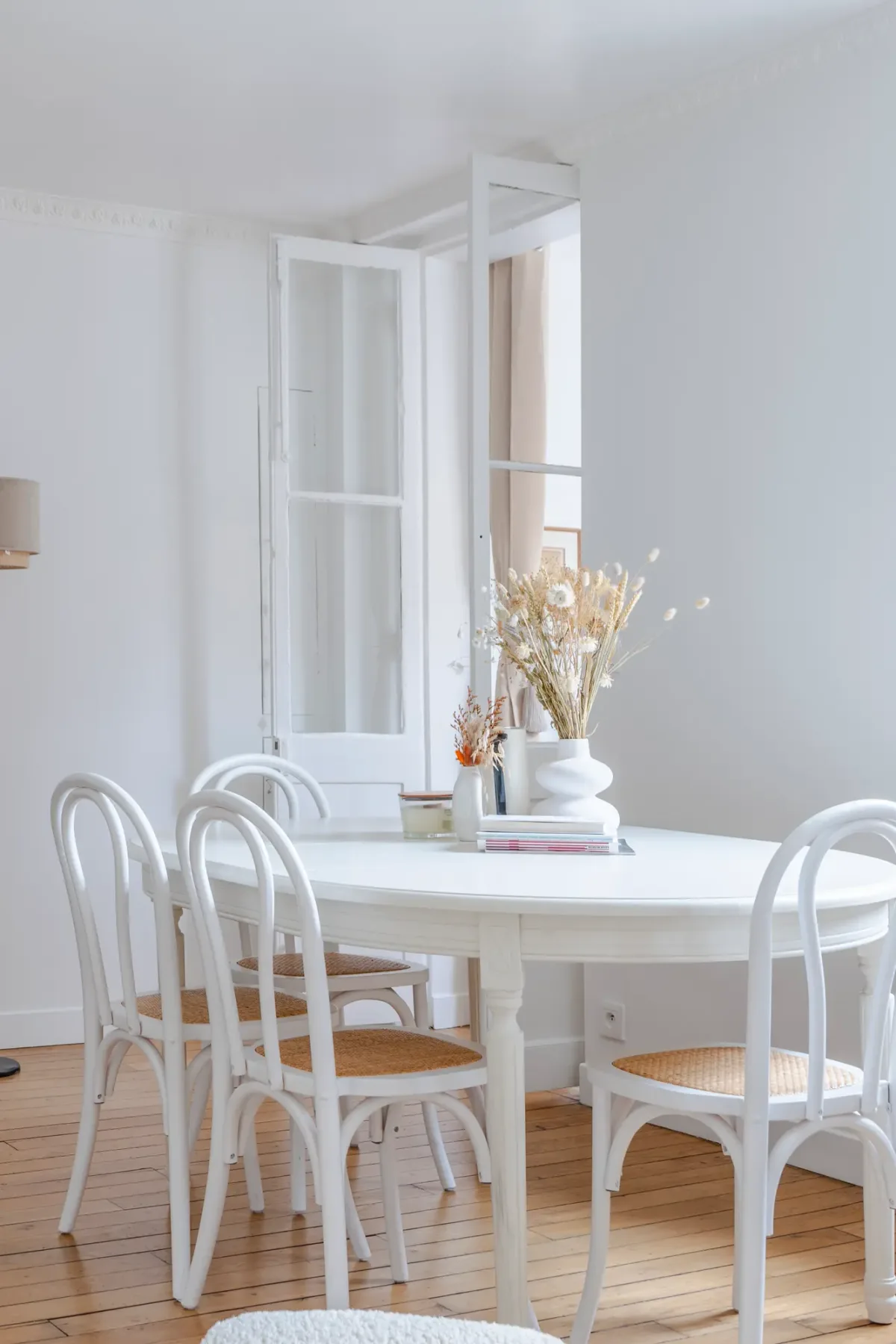A bright dining area with white seating around a table.