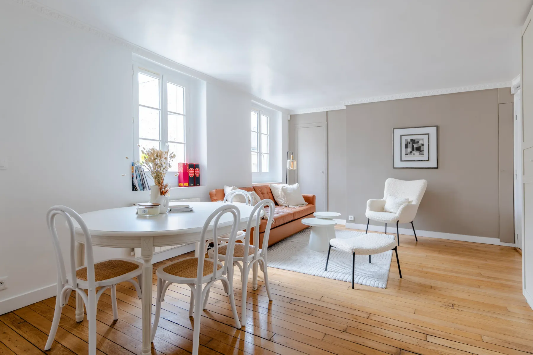 A bright living and dining area with a table, seating, and tall windows.