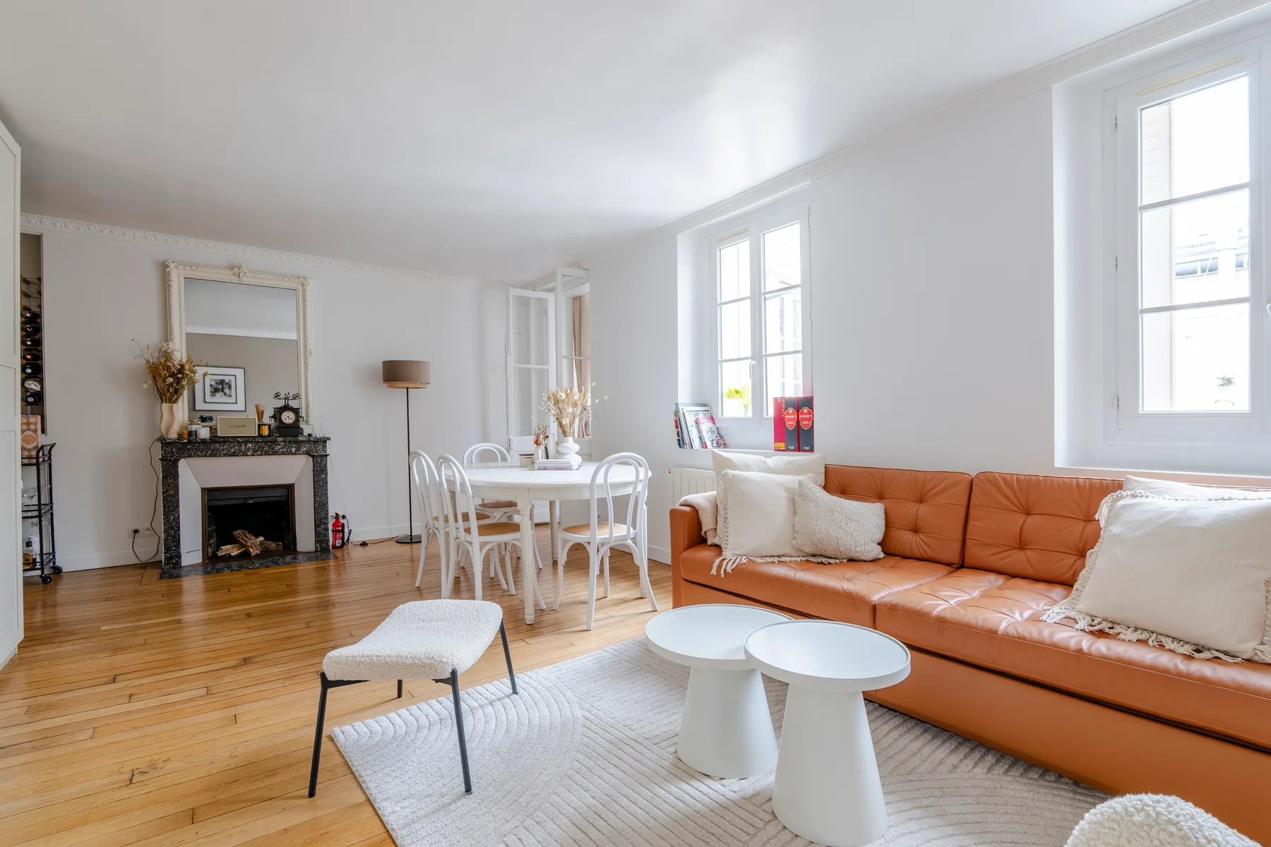 Una luminosa sala de estar y comedor con un sofá largo y una mesa blanca.