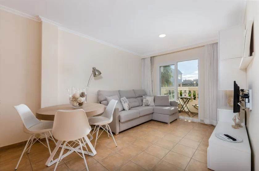 Living room with a dining area, corner seating, and glass doors opening onto a balcony.
